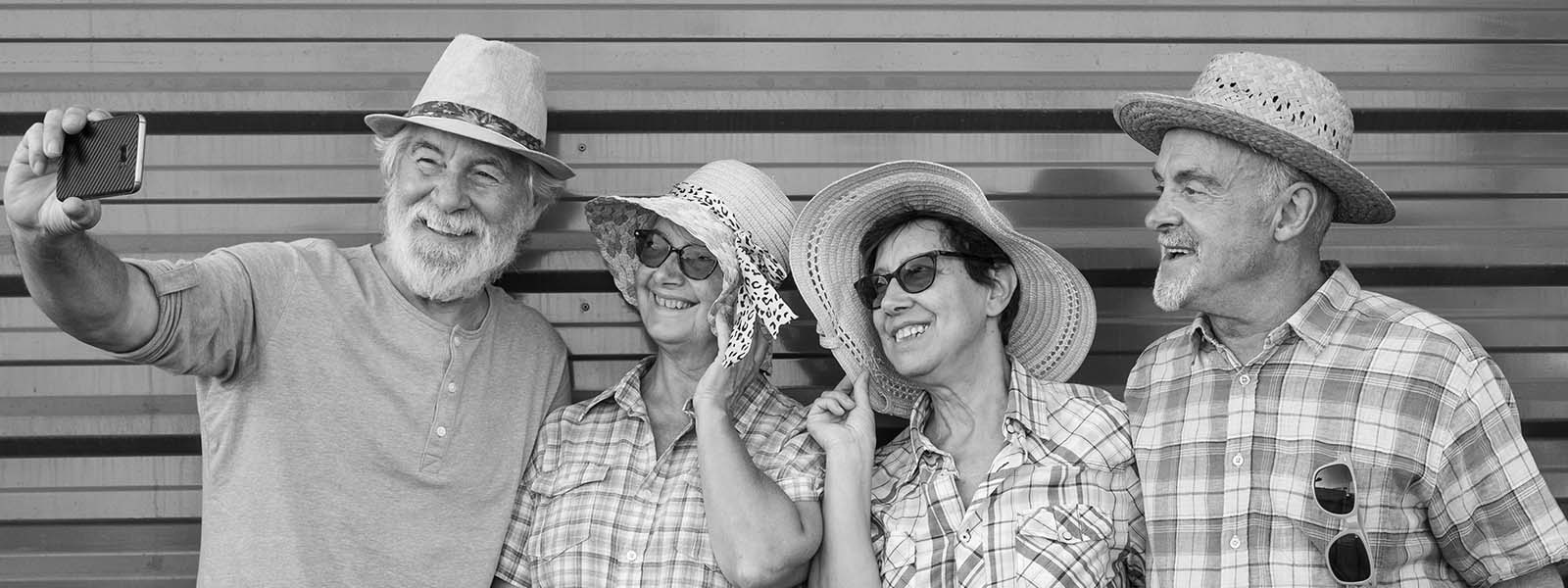 Black and white portrait of four senior people standing together for a selfie